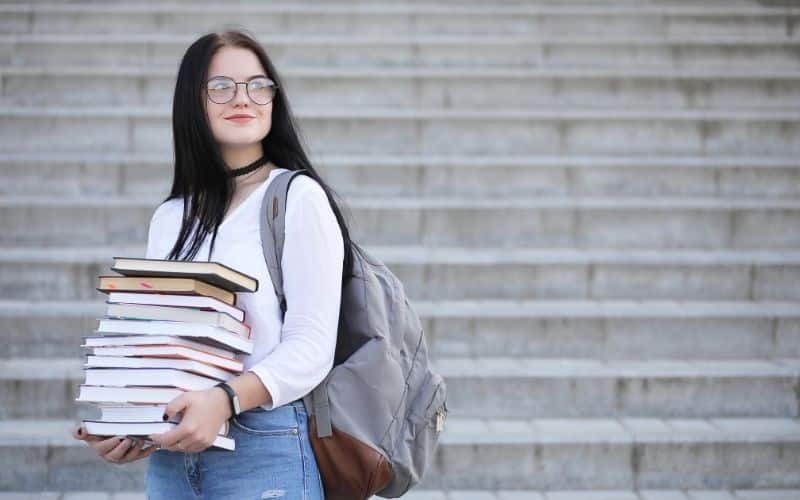 female student carrying stack of books