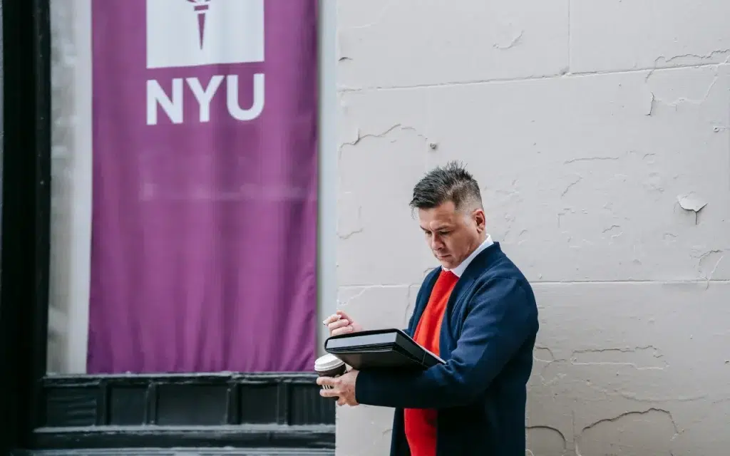 man reading on new york university campus against a wall