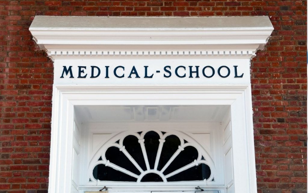 white door labeled medical school in brick wall