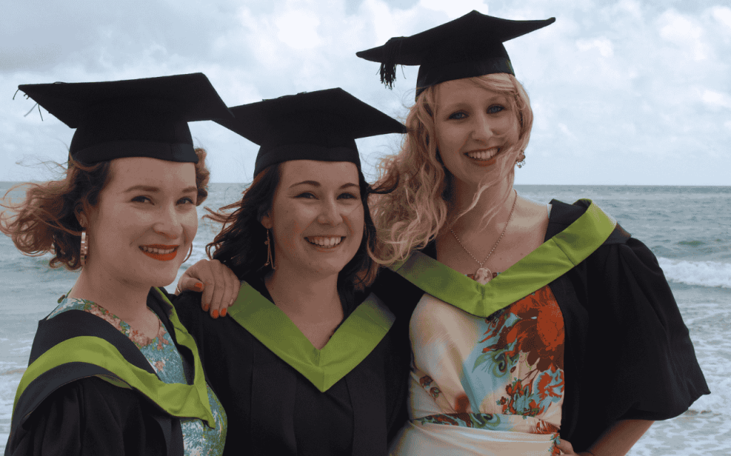 three florida college graduates on the beach