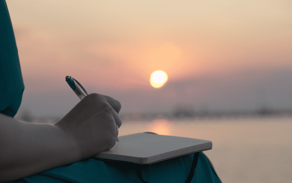 student with journal on the beach