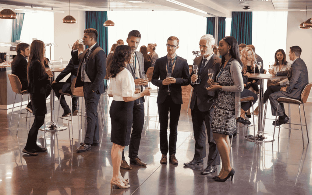 MBA students stand or sit with champagne glasses at a networking event