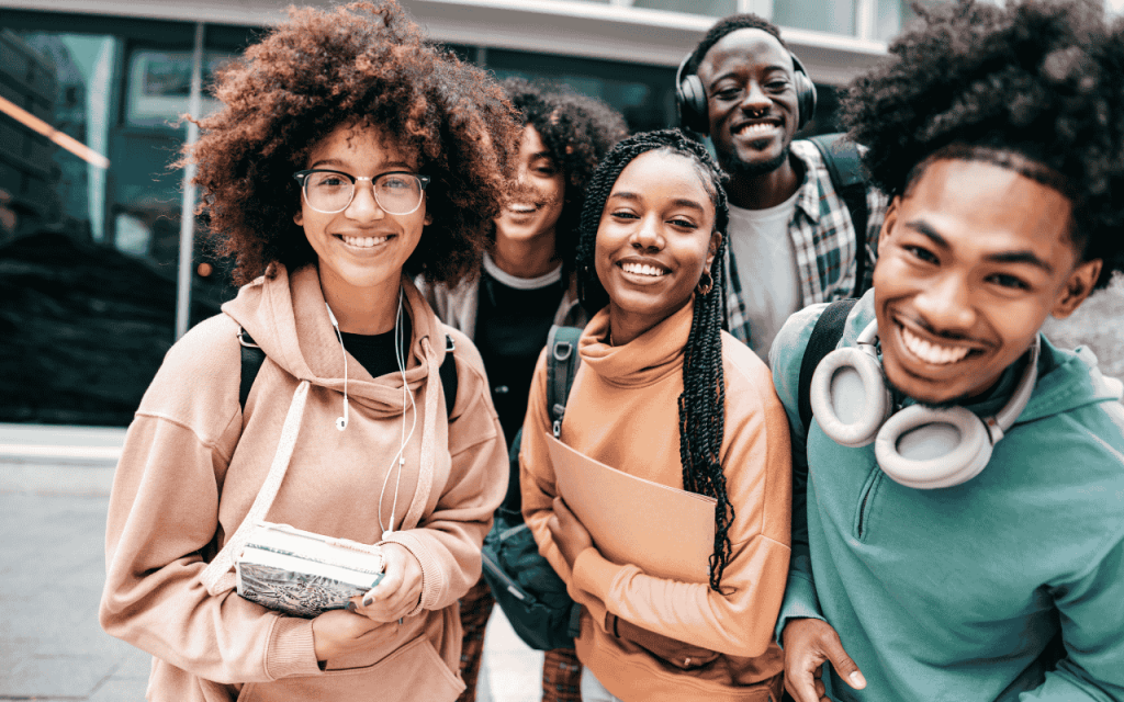 five african american MBA students smile with headphones, notebooks, and backpacks