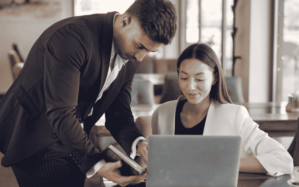 man in suit explains class material to woman with laptop pursing MBA