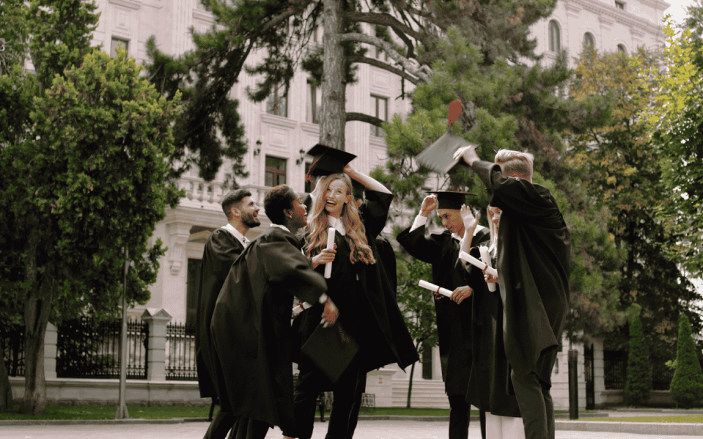 MBA graduates celebrate in a park with their cap and gowns