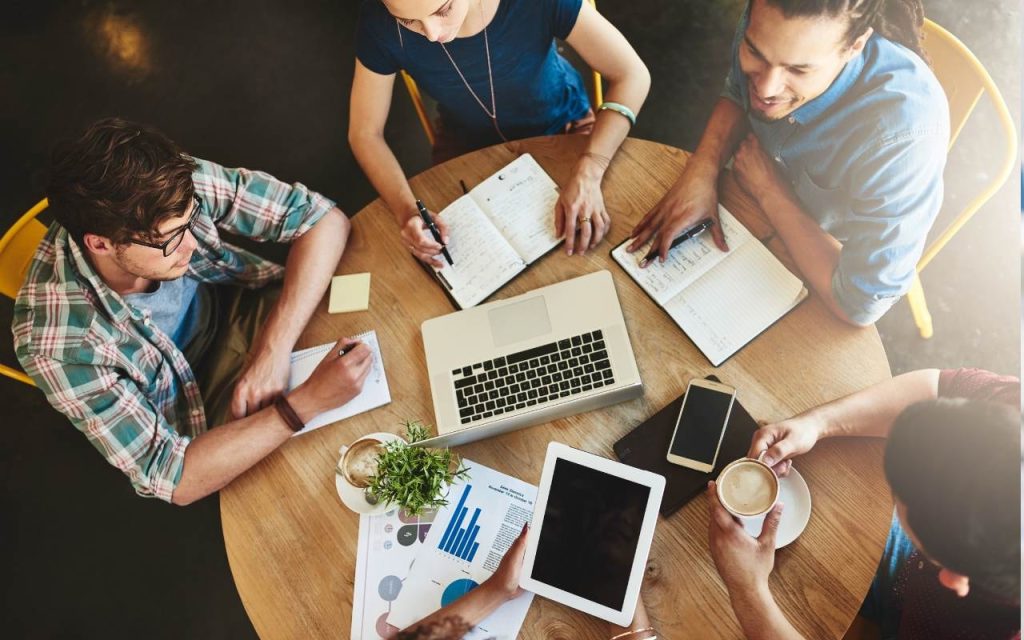 aerial view of undergraduate students around wood table