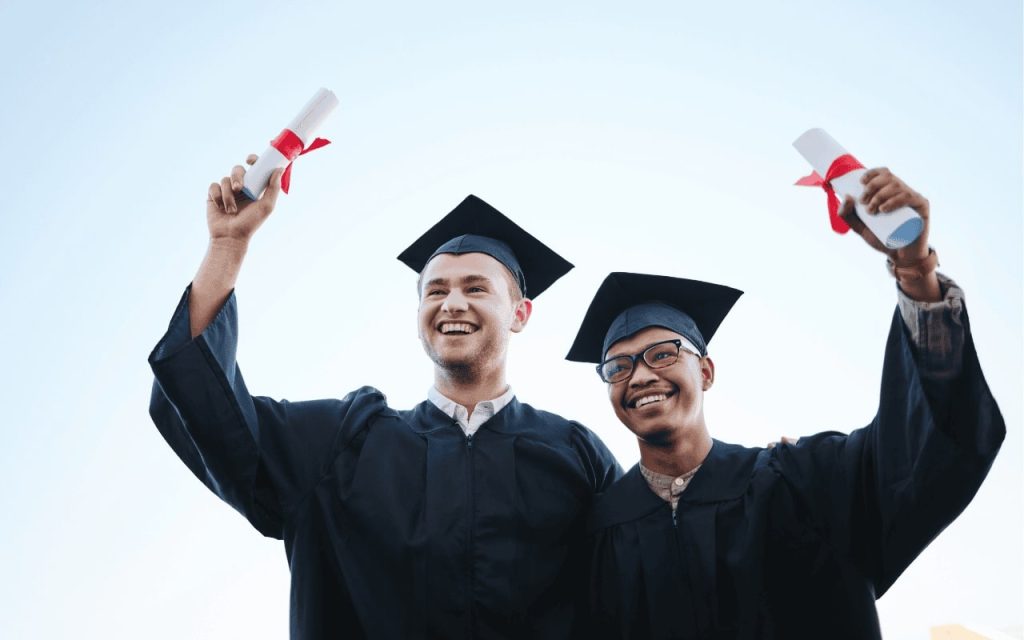 two graduates pose with diplomas in cap and gowns