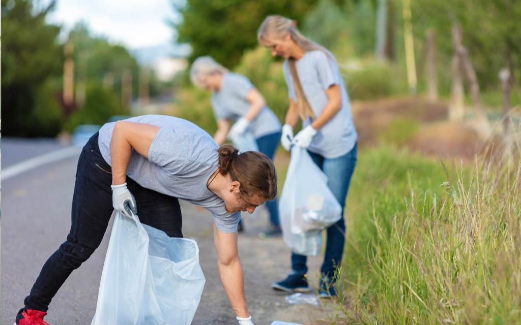 student volunteers collect litter off road