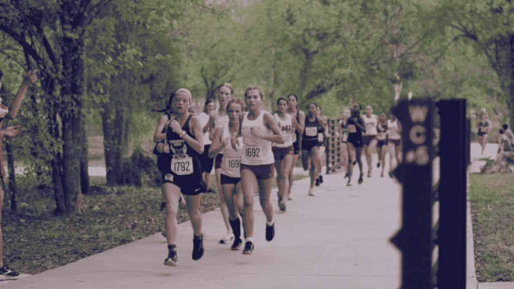 student athletes running with trees in background