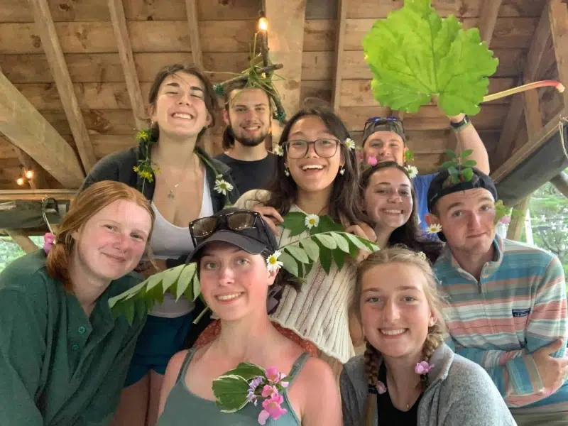 students pose with leaves in a wood cabin