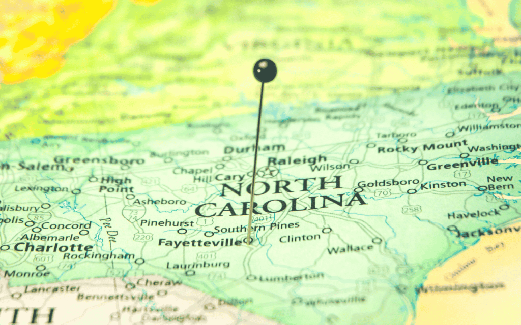 paper map of north carolina with a pin sticking out of it