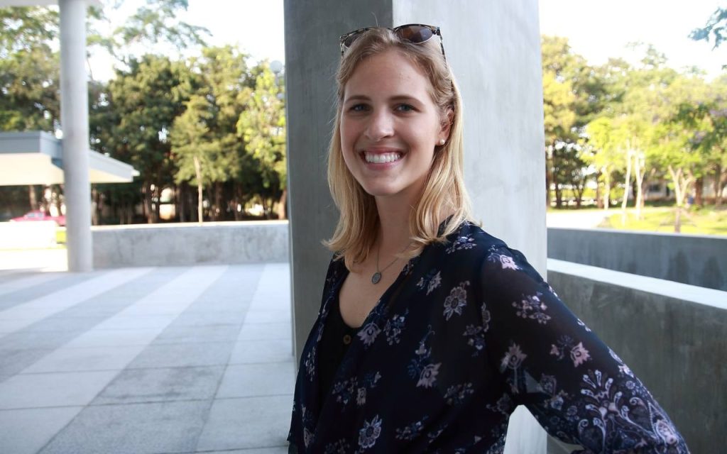 smiling woman stands on sunny UNT campus