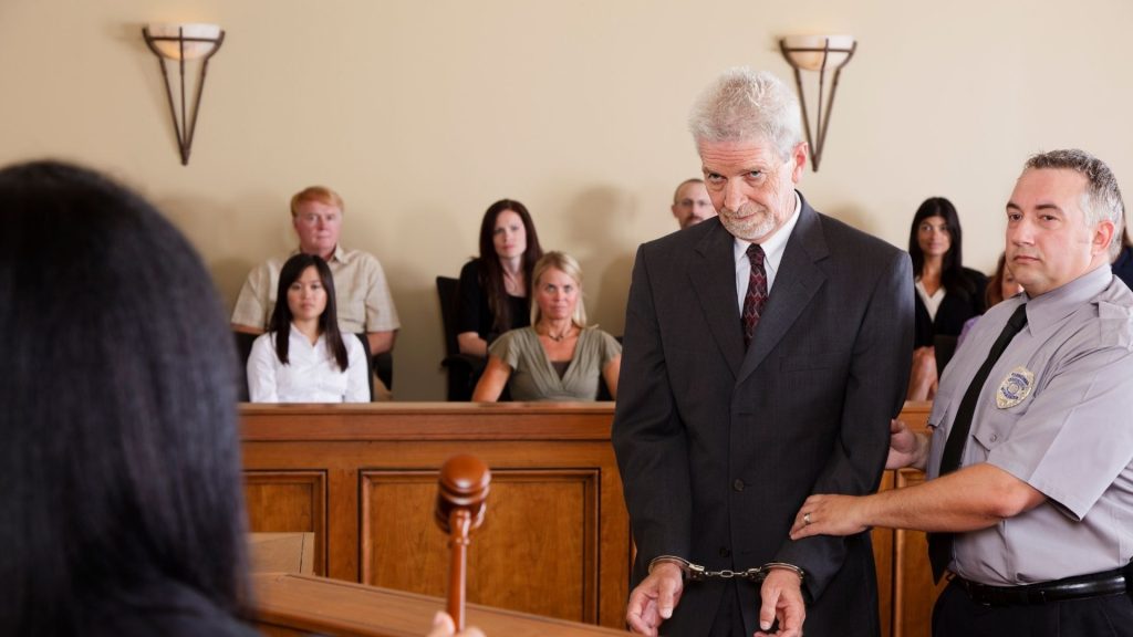 handcuffed man stands trial in courtroom