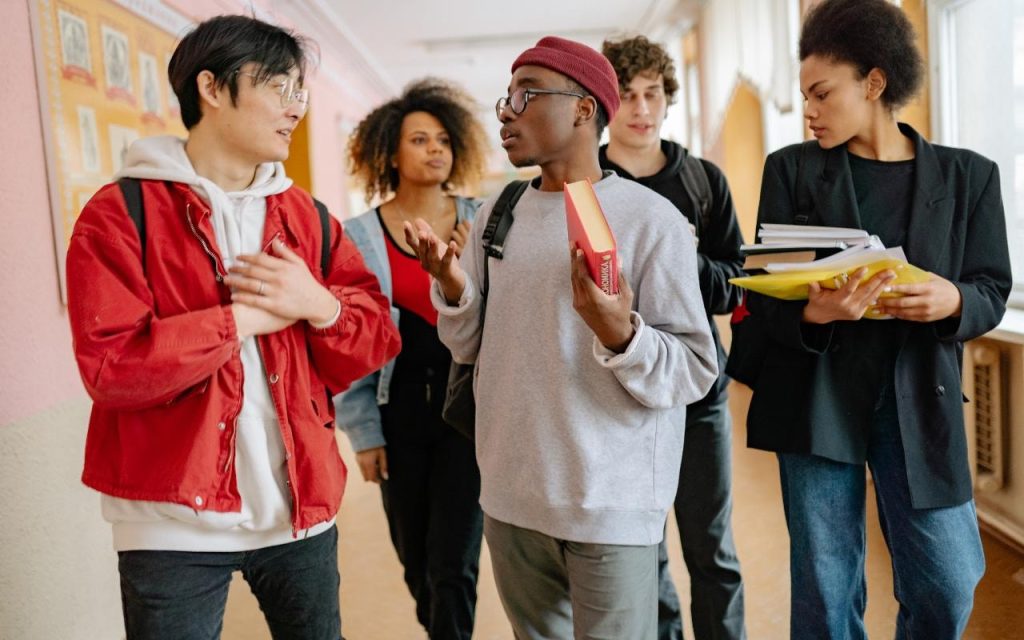 group of college students walking in hall with books