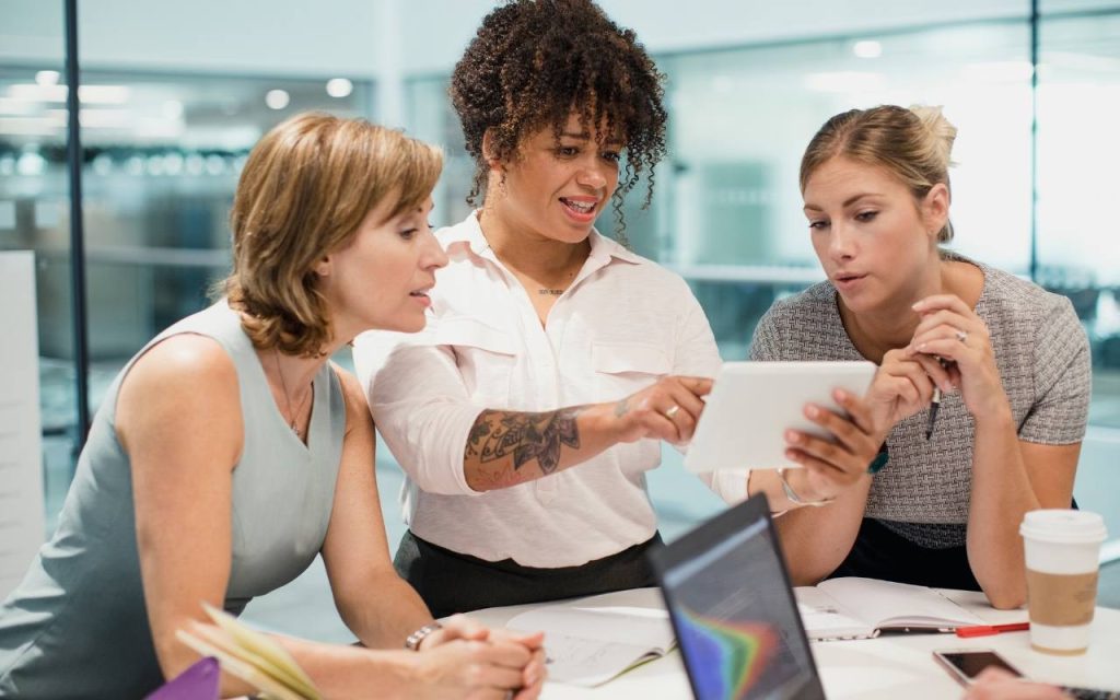 three women discuss around a table