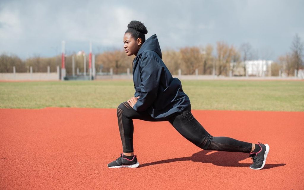 track athlete stretches on the field