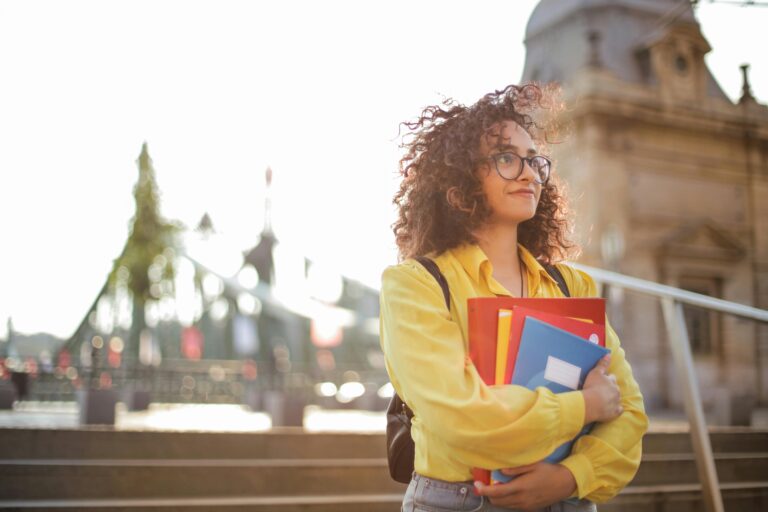 Girl holding books in front of school building